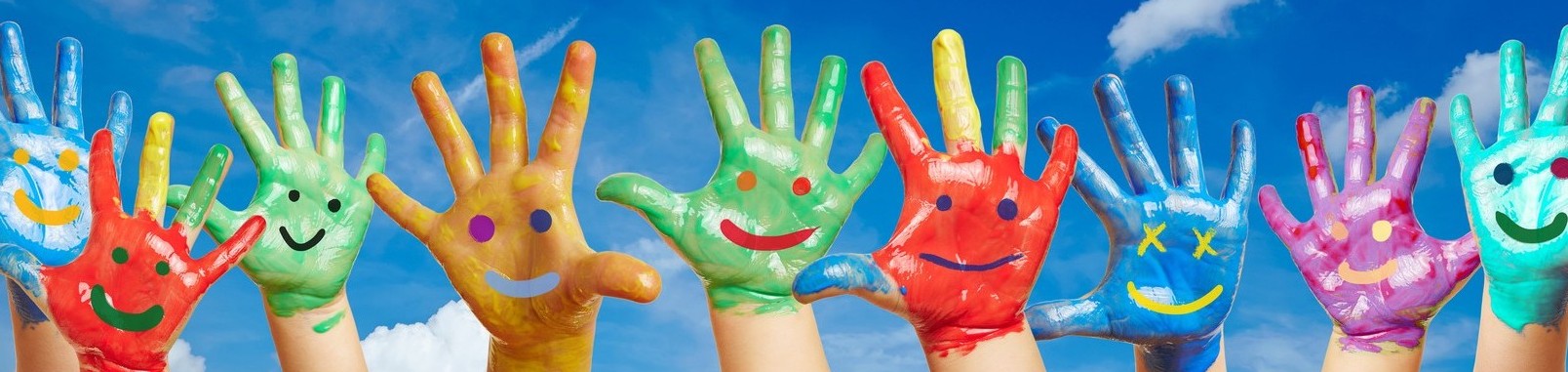 Bunte Kinderhände mit aufgemalten Smileys vor einem Himmel