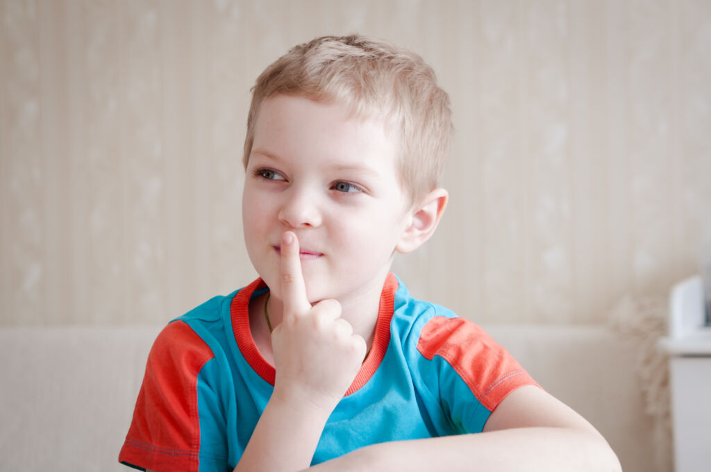 Ein kleiner Junge mit seinem Zeigefinger vor dem Mund